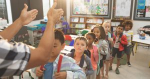 Front view of school kids standing and forming a queue in classroom at school